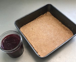 traybake tin lined with pastry and a jar of jam beside it